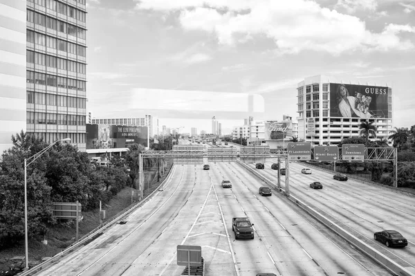 Highway or roadway with cars and skyscrapers on cloudy blue sky. Road with traffic signs for transport vehicles. Billboards on buildings. Public infrastructure concept — Stock Photo, Image