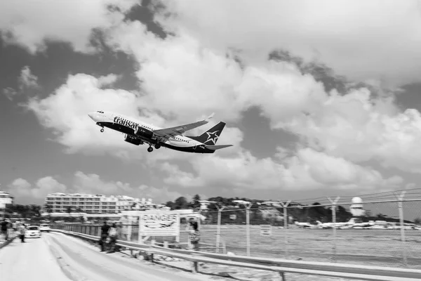 Philipsburg, Sint Maarten - February 13, 2016: plane low fly over maho beach. Jet flight land on cloudy blue sky. Airplane in sunny clouds. Beach vacation at Caribbean. Wanderlust, travel and trip — Stock Photo, Image