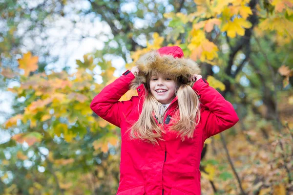 Elrejtése hangulatos hood vagy fok felett. Gyermek szőke hosszú haj meleg kabát szabadtéri séta. A réteg boldog lány élvezze őszi természetvédelmi park. Gyermek viselni divatos kabátot kapucnival. Esik a ruhák és a divat fogalma — Stock Fotó