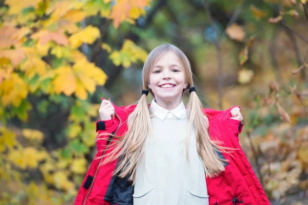 子金髪長い髪暖かいジャケット屋外で歩きます。幸せの赤いコートの女の子は、天気の良い秋のパークをお楽しみください。子供服おしゃれなコート。秋の服とファッションのコンセプト。快適なのんきな — ストック写真