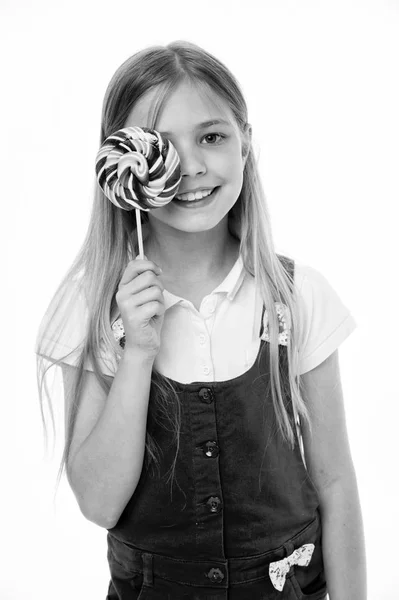 Flicka äter stora godis på pinne eller lollipop. Flicka på leende ansikte håller jätte färgglada lollipop i hand, isolerad på vit bakgrund. Barn med långt hår gillar sötsaker och fester. Sweet tooth koncept — Stockfoto