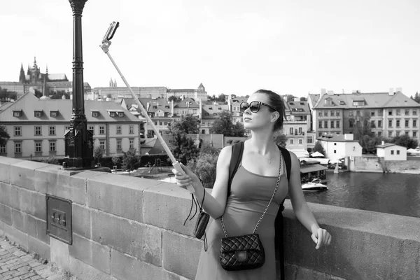 Frau macht Selfie mit Handy in Prag, Tschechische Republik. Frau mit Smartphone am Stock an Brücke über Fluss Touristinnen mit modischem Look und sinnlicher Schönheit. Reisen und Stadtbesichtigung — Stockfoto