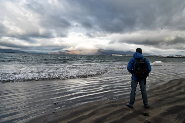 O homem olha no horizonte com paisagem marinha de reykjavik em iceland. conceito de metas futuras. amantes da natureza. viagem e luxúria. o homem na costa do mar olha na paisagem marítima que está perto da água. céu dramático na Islândia — Fotografia de Stock