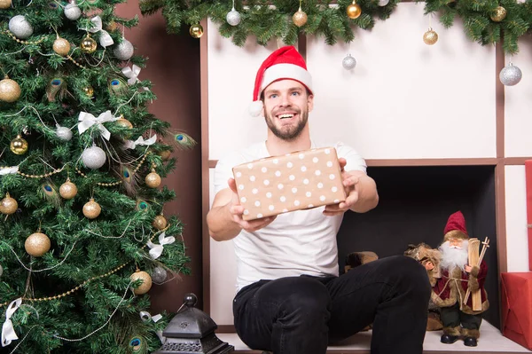Ευτυχισμένος άνθρωπος δίνουν παρόν πλαίσιο στο χριστουγεννιάτικο δέντρο και τζάκι — Φωτογραφία Αρχείου