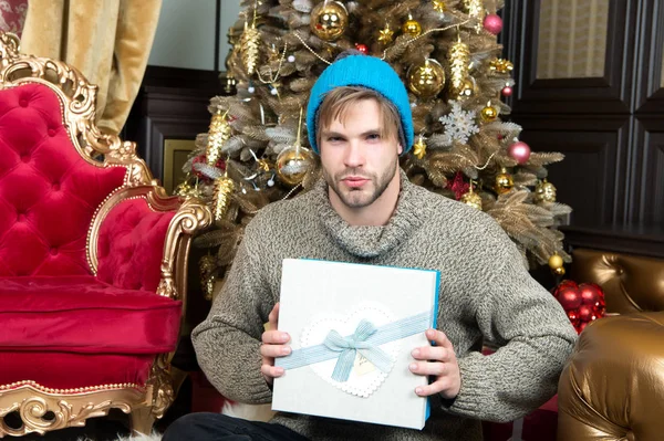 Hombre con caja de regalo sentarse en el árbol de Navidad — Foto de Stock