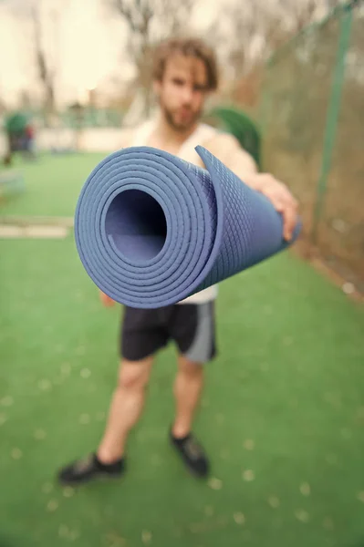 Joga, fitness Mata niebieski kolor w rękach muskularny mężczyzna — Zdjęcie stockowe