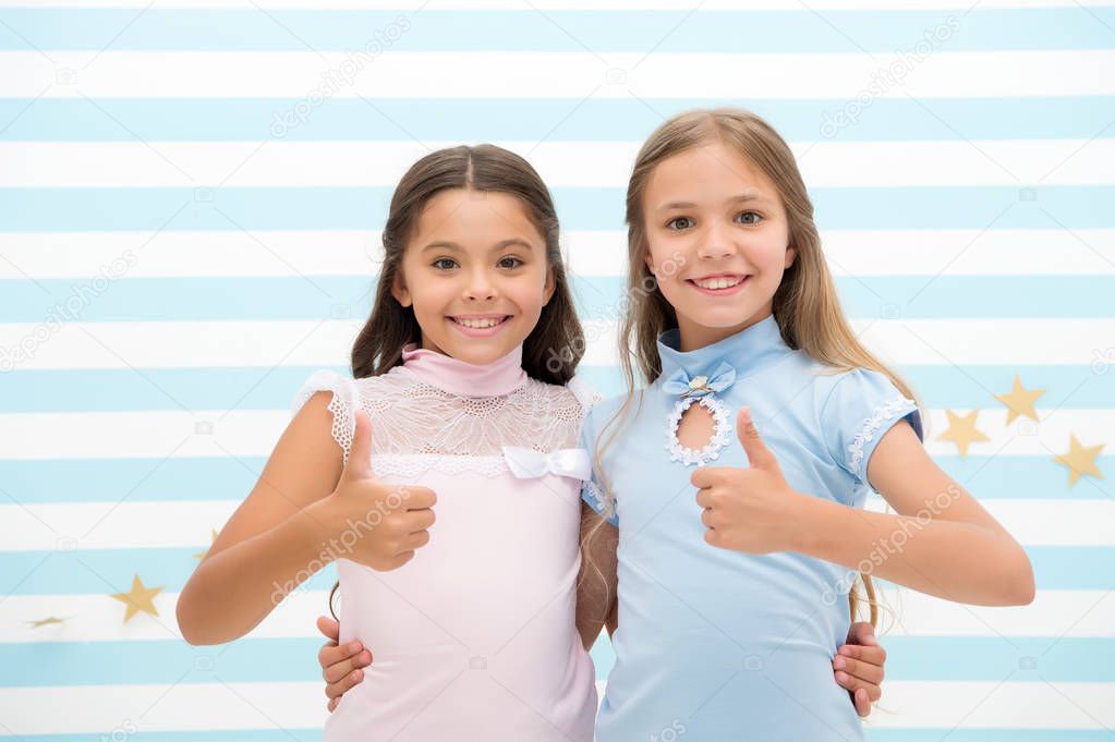 Girls smiling happy faces hug each other and show thumbs up gesture. Girls children best friends hugs. Happy childhood concept. Kids schoolgirls preteens happy together. Friendship from childhood