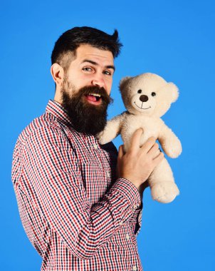 Adam oyuncak ayı mavi arka plan üzerinde tutar..