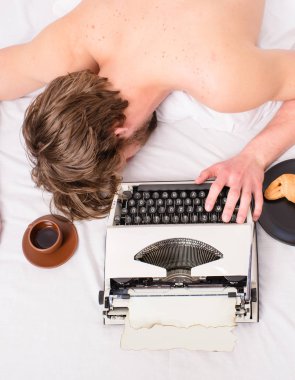 Yazar tousled saç yazma bölüm üstten görünüm sırasında uykuya. Daktilo kahve adamla yatakta yatıyordu. Adam uykulu çalışma sırasında yatak örtüsü yatıyordu. Yazar eski moda daktilo kullanılan. İşkolik uykuya.