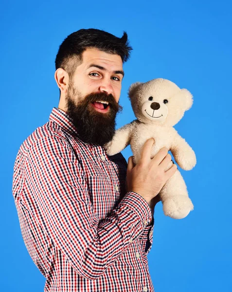 Man holds teddy bear on blue background.