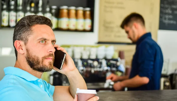 Man speak mobile phone and drink coffee cafe bar background. Man solving problems phone drink coffee. Confident entrepreneur communicate mobile. Start great day. Traditional beginning of his day