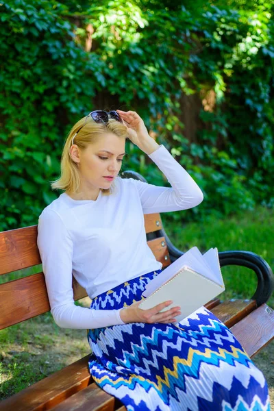 Favoritbok. Kvinna blondin tar paus avkopplande i parken läsebok. Flickan sitter bänk avslappnande med bokar, grön natur bakgrund. Tjej sugen på boken Uppehälleläsning. Läsa litteratur som hobby — Stockfoto