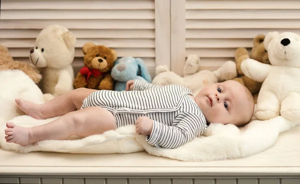 Niño con traje de cuerpo a rayas. Bebé acostado en edredón blanco — Foto de Stock