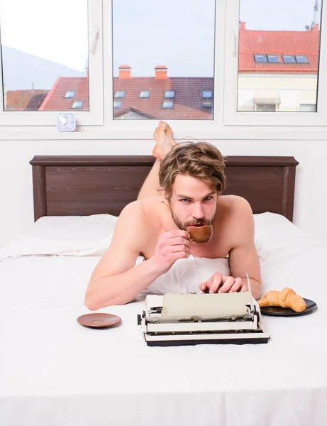 Szerző reggelizés ágy kávét iszik. Reggel ihletet. Kávé inspirálja őt, hogy írjon. Férfi író dolgozik könyv ágy ágynemű feküdt. Író romantikus szerző használt régi vágású írógép — Stock Fotó