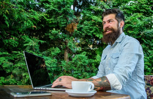 Hipster freelancer lavoro online blog notebook. Uomo barbuto uomo d'affari sedersi terrazza con computer portatile e una tazza di caffè. Beneficio freelance. Creare contenuti per blog web. Blogger creare post mentre godere di caffè — Foto Stock