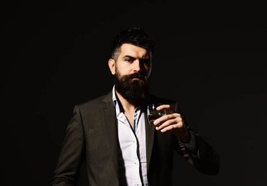 Ciddi yüzlü bir adam bir bardak alkolle kadeh kaldırıyor.