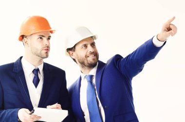 Proje yönetimi, yapı, inşaat kavramı. Gülümseyen iş adamı ve genç işçi ve ciddi yüzler. Mutlu patron bir şey çalışan için işaret. Kask içinde mevcuttur ve inşaat yöneticileri