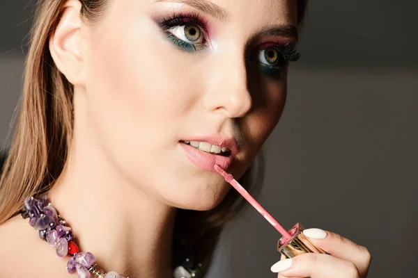 Menina com maquiagem colorida pintura lábios com brilho labial — Fotografia de Stock