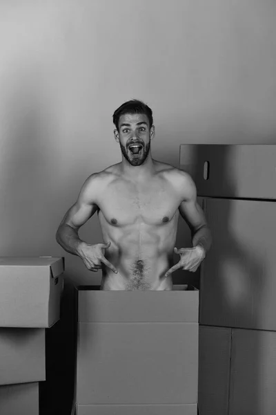 Hombre entre cajas señalando sus genitales cubiertos por cartón — Foto de Stock