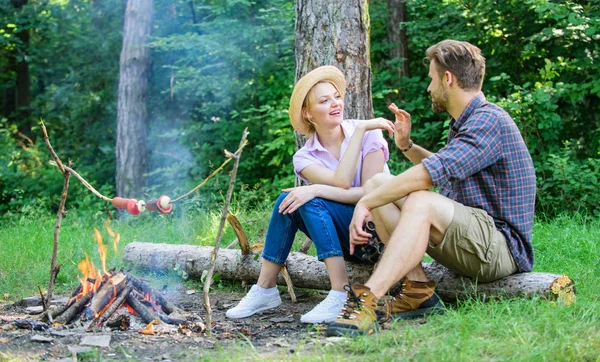 Pleasant smell of roasted food makes picnic atmosphere perfect. Picnic roasting food over fire. Idyllic picnic date. Family enjoy weekend in nature. Couple in love relaxing sit on log having snacks — Stock Photo, Image