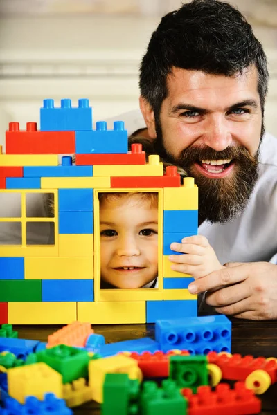Papá y el niño se esconden detrás de la casa hecha de bloques de plástico — Foto de Stock