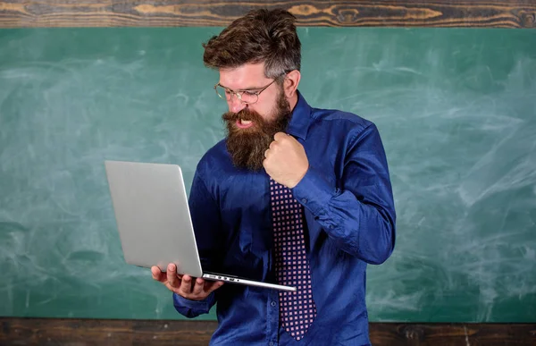 Slowly internet annoying him. Annoyed by slow internet. Hipster teacher aggressive with laptop goes mad about slow speed internet connection. Teacher bearded man modern laptop chalkboard background — Stock Photo, Image