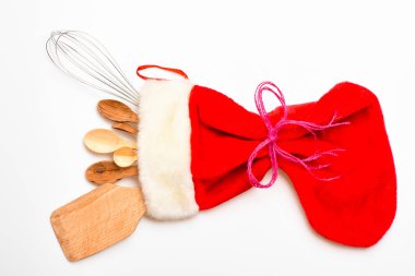 Noel hediye kavramı. Mutfak aksesuarları veya mutfak seti büyük kırmızı çorap, beyaz arka planda Paketli. Tahta kaşık ve çırpma teli olarak mutfak eşyaları Noel çorabına yatıyordu. Mutfak aksesuarları veya araçları