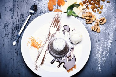 Konsept: Restoran menüsü, sağlıklı beslenme, ev yapımı ve su kabağı. Portakallı erişteli çikolatalı beyaz tabak ve kirli gri arka planda dondurma. Fındık ve tereyağı dekoru