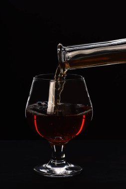 Brandy or cognac filling glass from bottle.