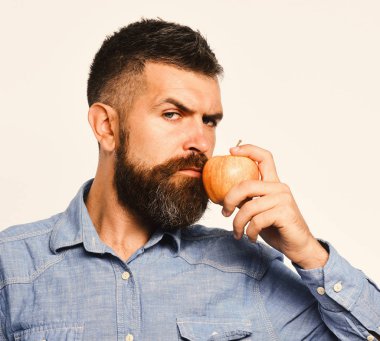 Sakallı adam beyaz arka planda kırmızı meyveler tutuyor.