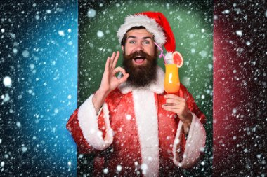 Yakışıklı, sakallı, uzun sakallı Noel Baba. Elinde Noel 'de alkolsüz kokteyl bardağı tutan uzun sakallı Noel Baba. Ya da Noel süveteri ve renkli stüdyo arka planında güzel görünen yeni yıl şapkası olan.