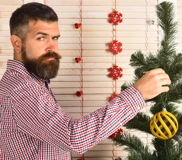 Mann mit Bart im karierten Hemd hält goldene Weihnachtskugel in der Hand. — Stockfoto