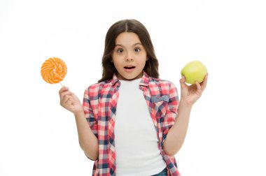 Şeker tatlısı bizi mutlu edebilir mi? Tatlı gülen kız elinde lolipop ve elma tutuyor. Okulun öğle yemeği alternatifleri. Kız izole edilmiş tatlı şekerleri seviyor. Aynı tatlı elma ve şeker tadı