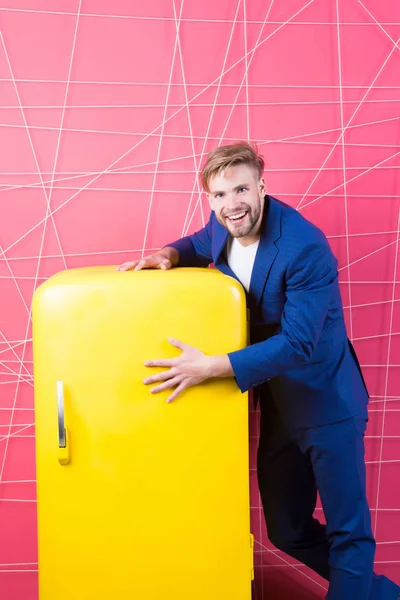Man formal elegant suit stand near retro vintage yellow refrigerator. Vintage household appliances. Bachelor hungry guy think what eat near fridge. Bright fridge household appliances interior object