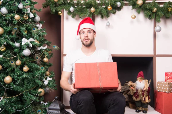 Man santa met verbaasd gezicht houden aanwezig bij de kerstboom — Stockfoto