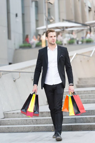 Guy carry bunch shopping bags. Profitable deals shopping on black friday. Man hold lot paper bags packages after shopping in mall. Black friday sale concept. Man formal suit carry shopping bags
