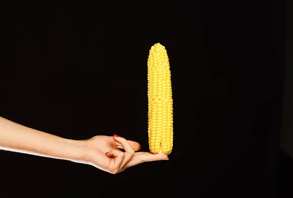 雌性手将玉米隔离在黑色背景中 — 图库照片