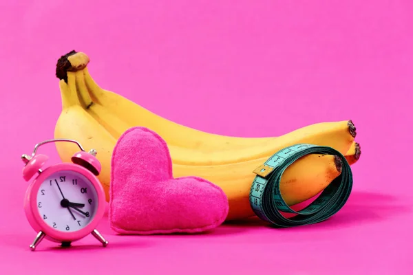 Rollo de cinta métrica y plátanos cerca del corazón y despertador — Foto de Stock