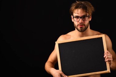 Adam seksi kas gövde yazı tahtası önünde çıplak onun Gövde tutun. Maço çekici çıplak adam blackboard tutun. Adam sakallı ve tousled saç siyah arka plan ile. Kara tahta reklam kopya alanı
