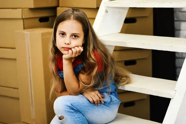 Niño se sienta en la escalera blanca por pila de cajas de cartón — Foto de Stock