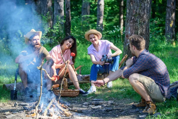 Hikers sharing impression of walk and eating. Weekend hike. Picnic with friends in forest near bonfire. Tourists with camera relaxing checking photos. Company having hike picnic nature background