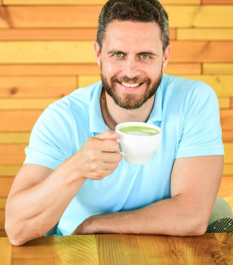 Cafe ziyaretçi mutlu yüz kahve kafein içecek keyfini çıkarın. Kafein yaratıcı suları akan zaman kullandığın verir azgınlık ve bunu takılıp alabilirsiniz. Adam sakallı adam ahşap masa café'de kapuçino içiyor