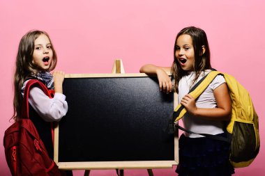 Okul çantası takan çocuklar parlak tahtaya yaslanıyor, kopyalama alanı