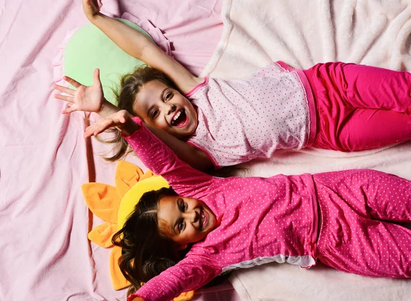 Kids with cheerful faces lie in bed. Schoolgirls in pajamas — Stock Photo, Image
