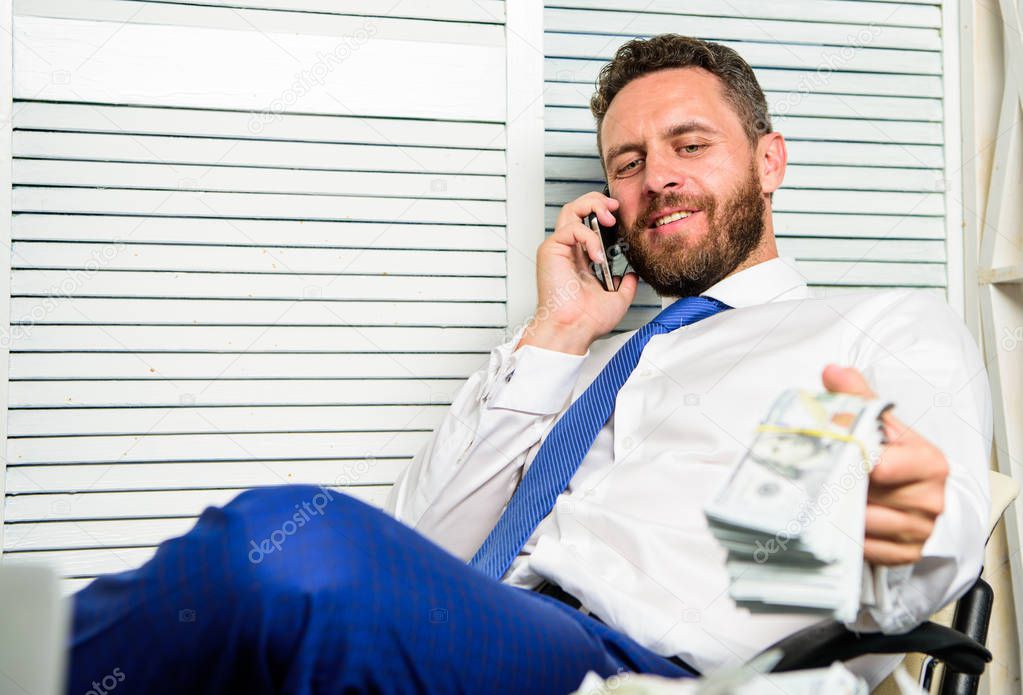 Businessman rich bearded guy sit office with lot of cash money. Bank loan or credit. Get cash in few minutes. Banking support line concept. Man successful businessman phone conversation ask service