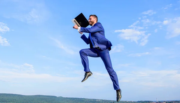 Повышение скорости онлайн. Бизнесмен ноутбук удовлетворен качеством. Человек с ноутбуком прыгать или летать в воздухе синий фон неба. Крупные интернет-провайдеры повышают качество связи. Быстрое подключение к Интернету — стоковое фото