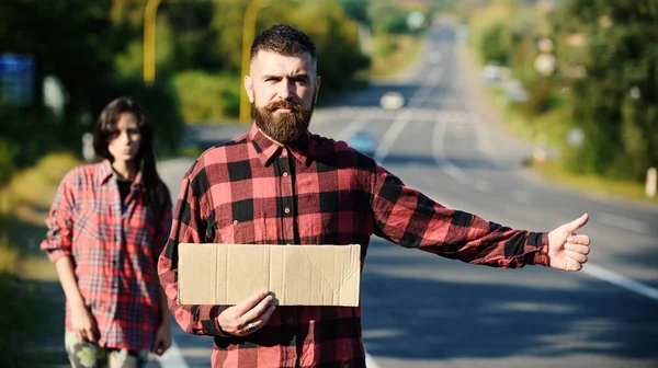 Hipster try to stop car with cardboard sign and thumb