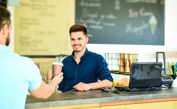 Enjoy your drink. Served coffee to go. Man ask for drink at bar counter. Barista at bar of modern cafe ready serve coffee for client. Barista handsome stylish hipster communicate with client visitor