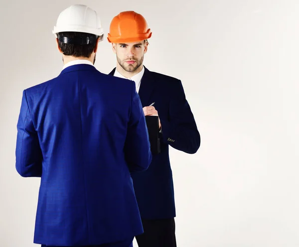 Entrepreneur and engineer back view. People in helmets isolated on white background. Architects think about project. Construction, business people, design concept. Engineers with serious faces