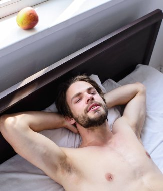 Adam tıraşsız yakışıklı adam çıplak gövde yatak rahatlatıcı. Adam seksi maço beyaz yatak örtüsü yatıyordu. Dinlenme adam uykulu uykulu tıraşsız sakallı yüzü. Çok iyi kavramı sakin ol. Bırak vücudun rahat hissediyorum